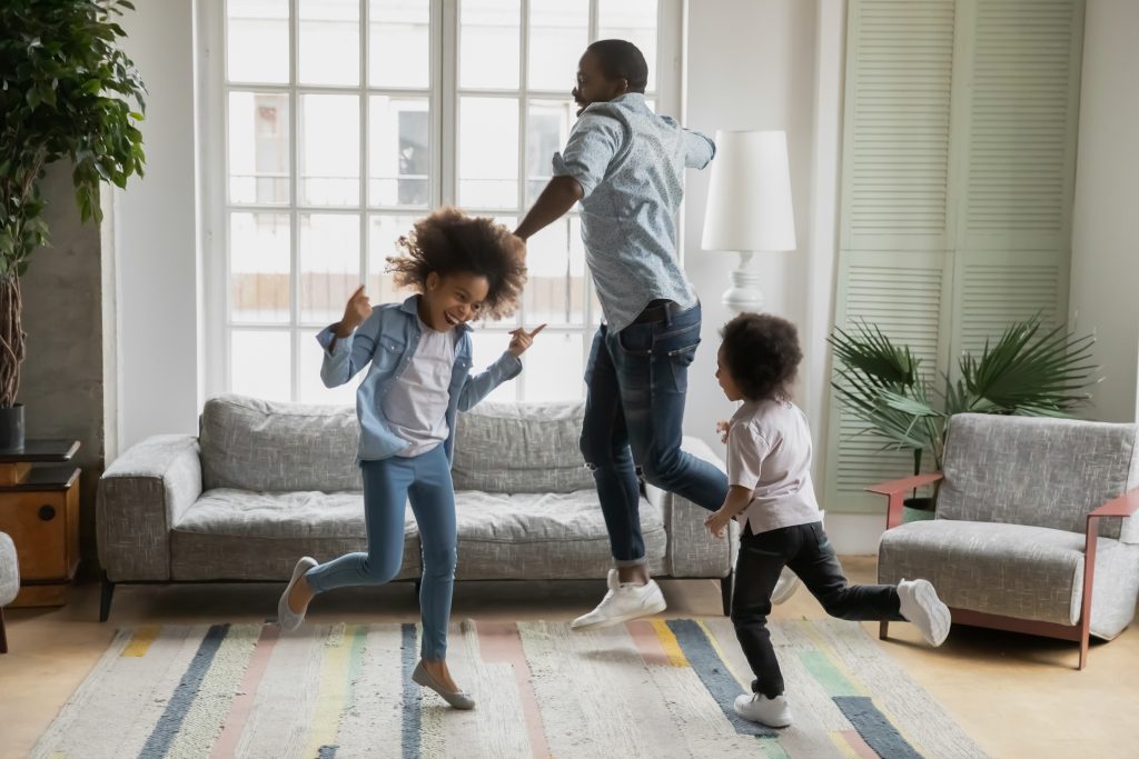 Een man en twee kinderen dansend door de woonkamer omdat hun huis lekker warm geisoleerd is